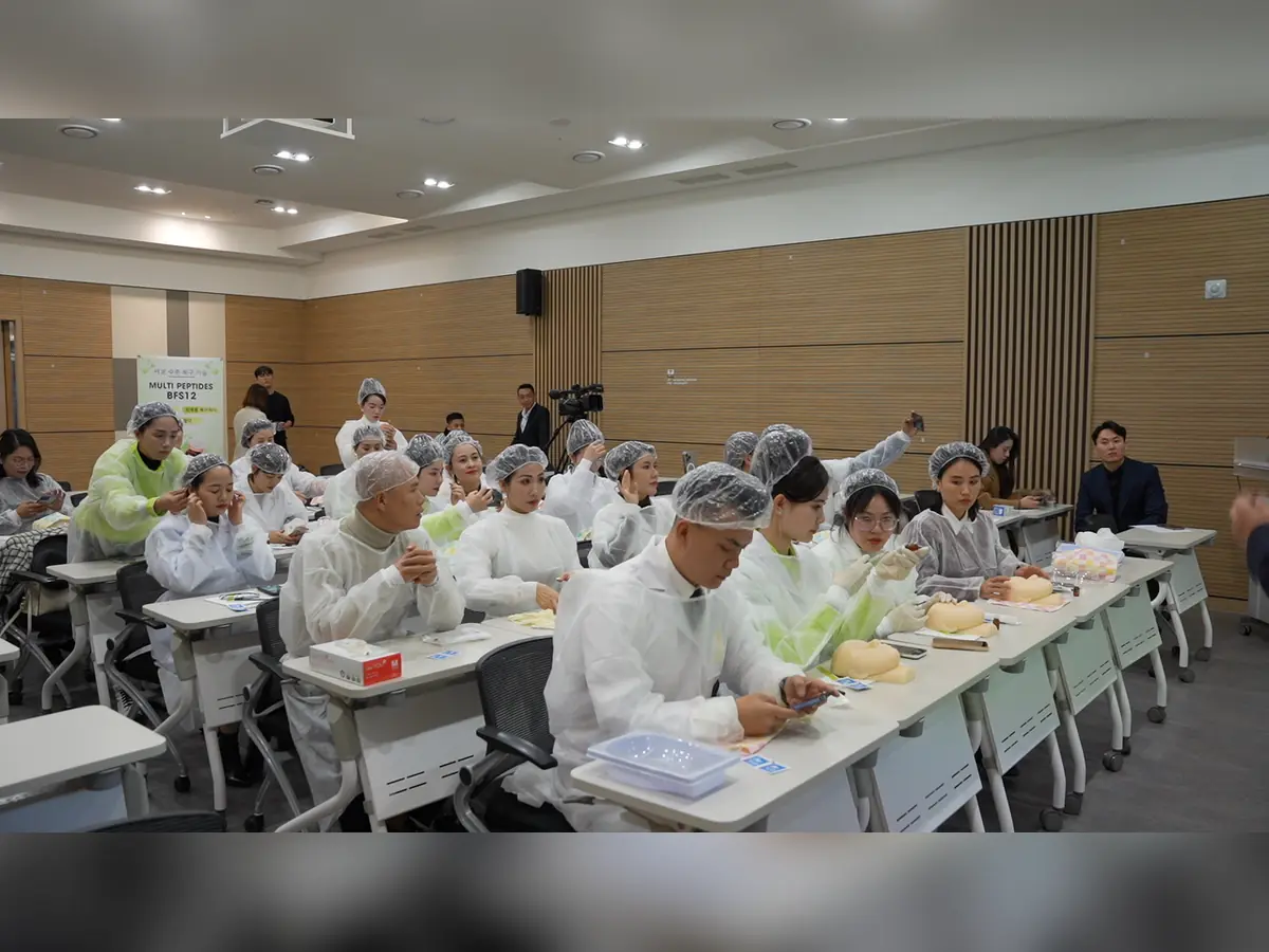 Học viên mặc áo bảo hộ và mũ trùm, thực hành trên mô hình tại bàn học.