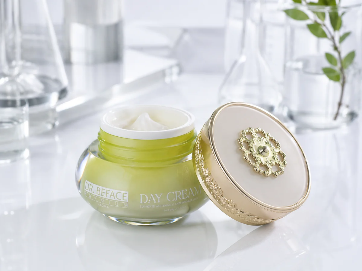 Hũ Day Cream mở nắp, cạnh nắp vàng trên mặt bàn kính.