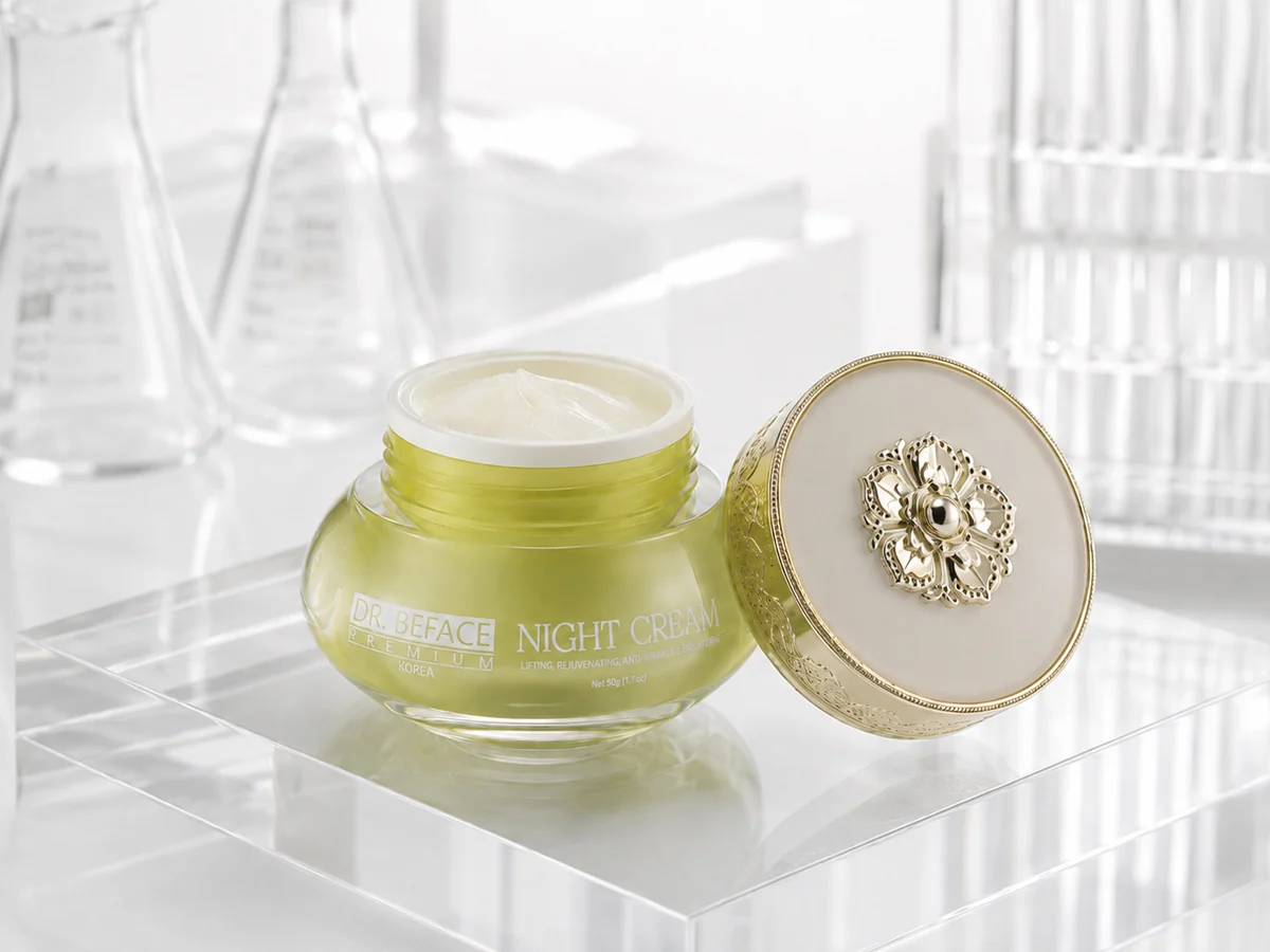 Hũ kem đêm DR.BEFACE PREMIUM® mở nắp trên bệ trong suốt, với nắp vàng đặt bên cạnh.