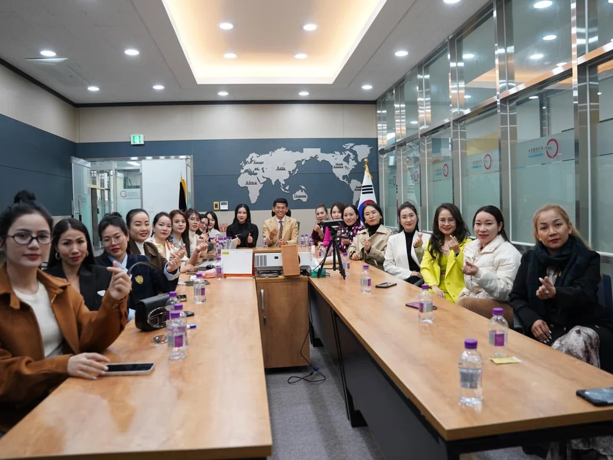 Đoàn tham quan ngồi quanh bàn dài trong phòng họp có tủ trưng bày sản phẩm.