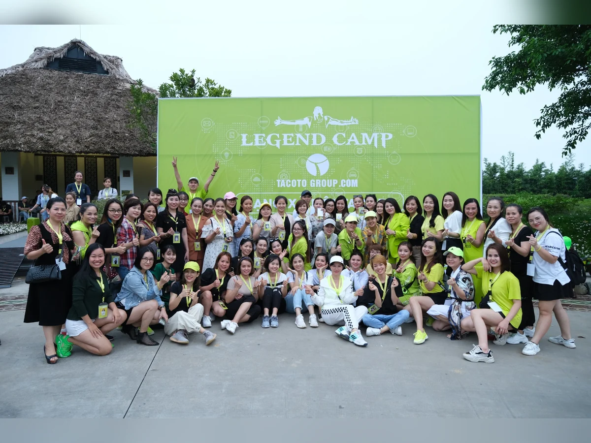 Tập thể thành viên chụp ảnh ngoài trời trước phông sự kiện Legend Camp.